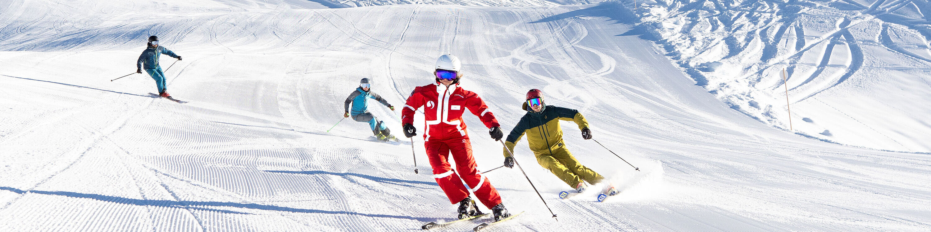 An advanced ski group is following their ski instructor, making easy turns