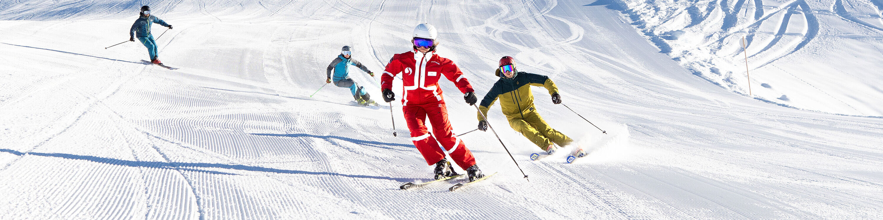An advanced ski group is following their ski instructor, making easy turns