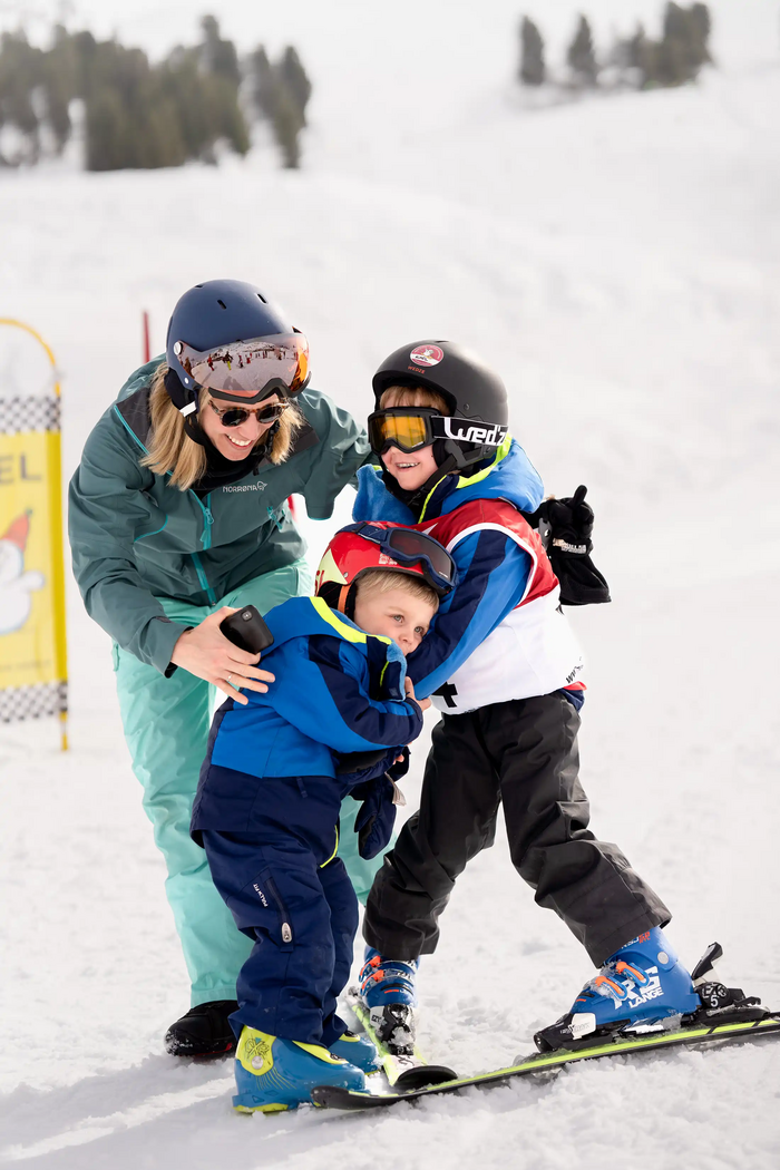 Een kind knuffelt een ander kind dat op ski's staat