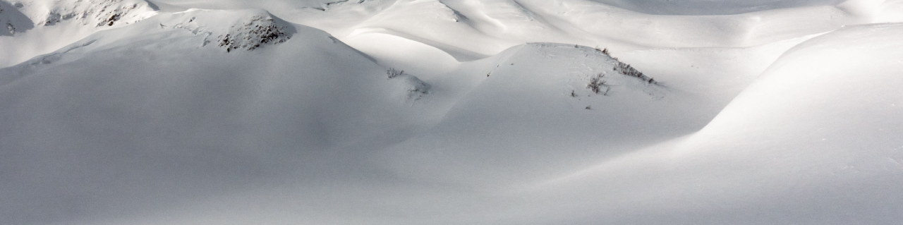 Ein Skitourengeher zieht seine Spur in einsamer, verschneiter Landschaft