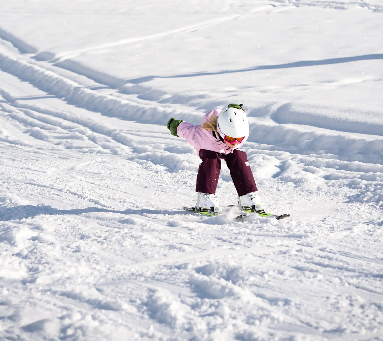 A child is zooming down the slope in a downhill position