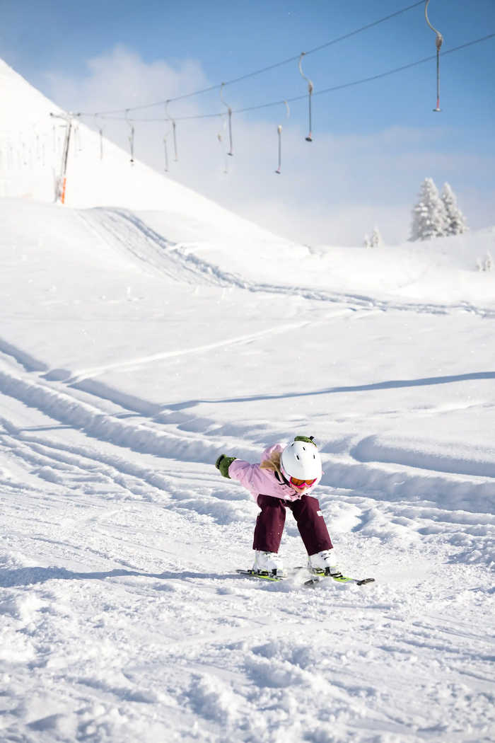A child is zooming down the slope in a downhill position