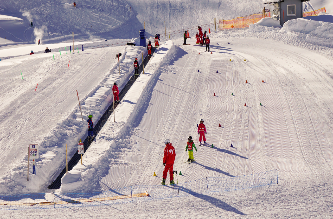 Kinderland van de kinderskischool Salober-Schröcken met verschillende skicursusgroepen op het tovertapijt en tijdens het oefenen op de piste